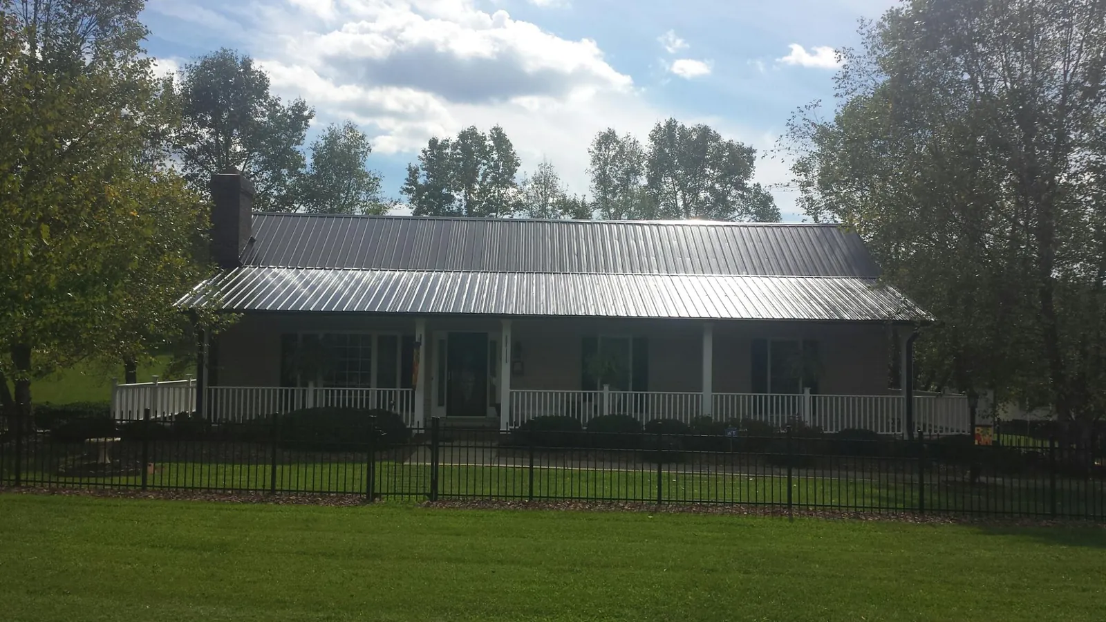 Gray metal roof on a brick ranch with a full width front porch — Gutter Guard Installation work by our crew in Osceola