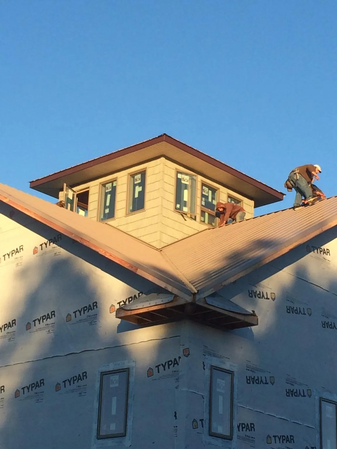 Roofers working around a rooftop cupola on a new metal roof at sunset — Roof Waterproofing in Osceola by Roofing Brothers